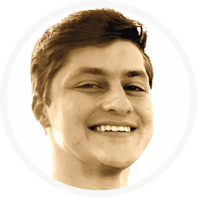 unnamed Ein junger Mann mit kurzen Haaren lächelt breit und blickt leicht zur Seite. Das Bild hat einen Sepiaton und einen schlichten weißen, kreisförmigen Hintergrund.